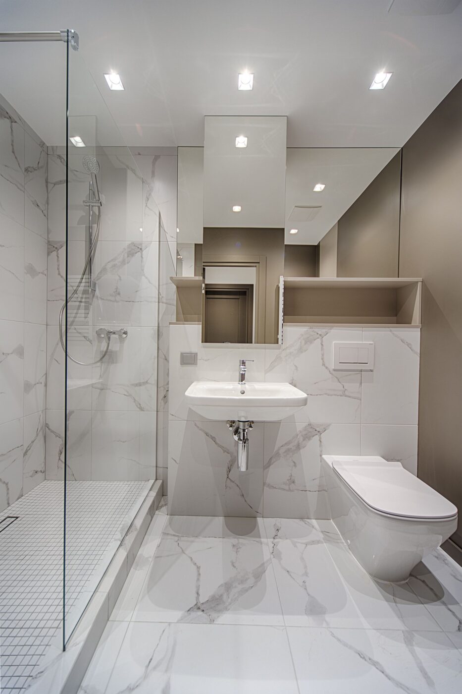 Badkamer met witte wastafel en ingebouwde douchecabine
